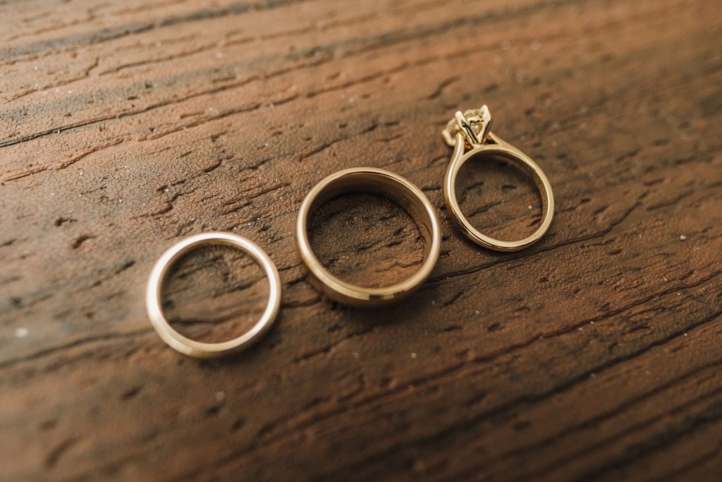 Three Sustainable wedding bands sitting on a wooden bench top