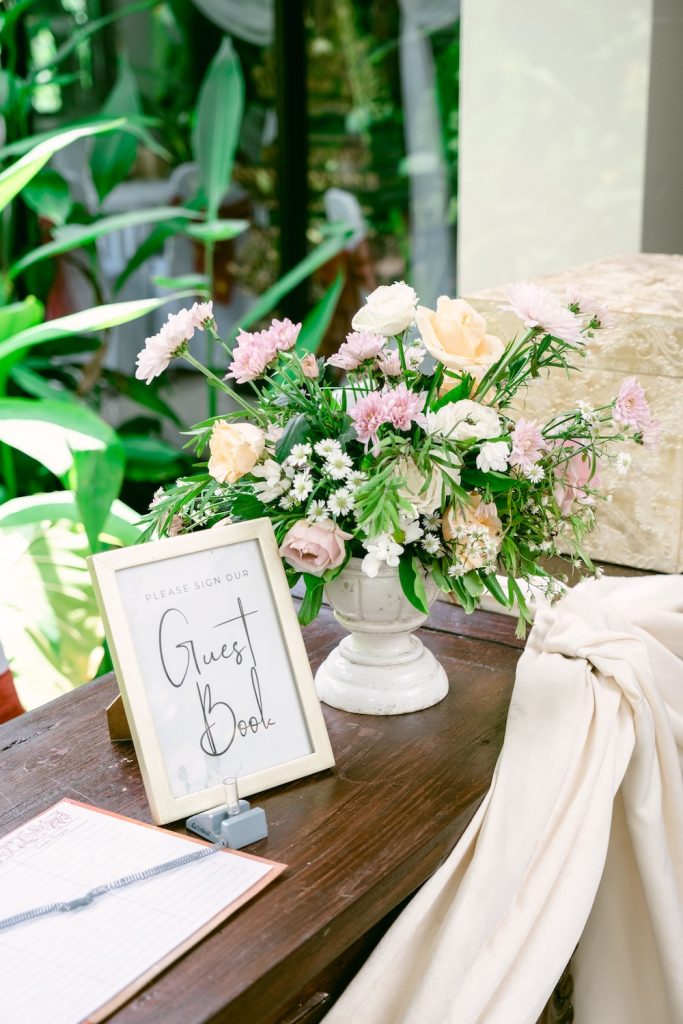 Wedding Guest book and vase of flowers sitting on a table