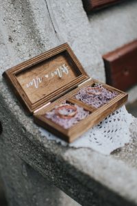 Wooden sustainable ring box sitting on a concrete ledge