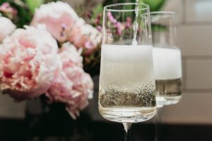 Two glasses of champagne at a wedding in front of a bunch of pink flowers