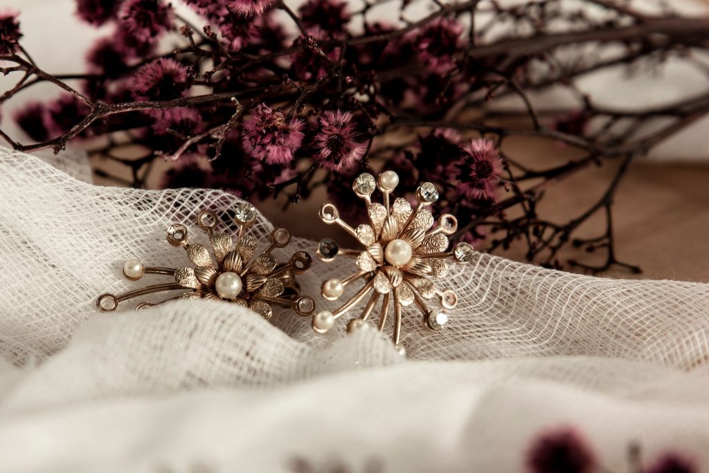 Wedding Jewelry sitting on a piece if fabric in front of some purple flowers