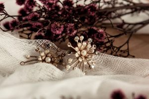 Wedding Jewelry sitting on a piece if fabric in front of some purple flowers