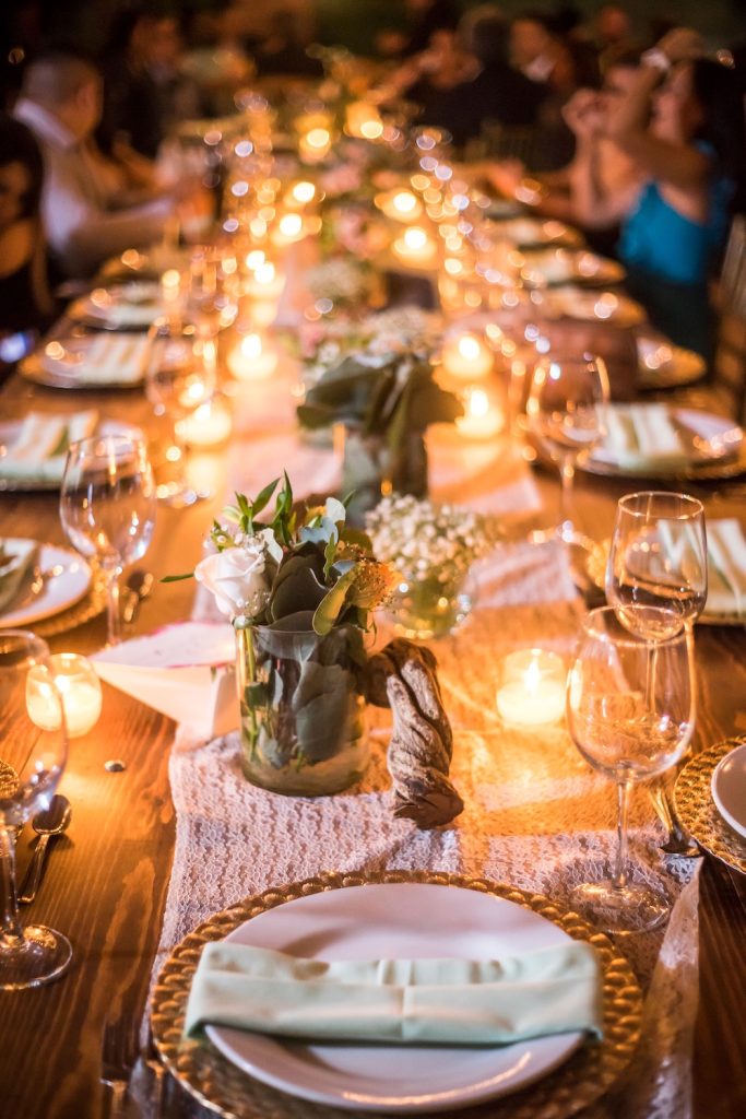 Sustainable rehearsal dinner with table set up with greenery and lights down the centre