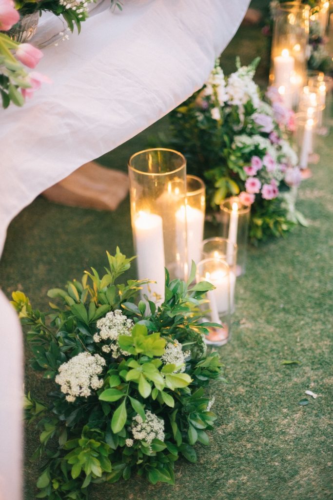 Wedding lighting and candles with greenery laid out on the grass