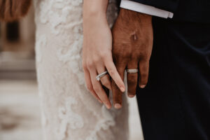 Bride and groom hands touching with their wedding bands on