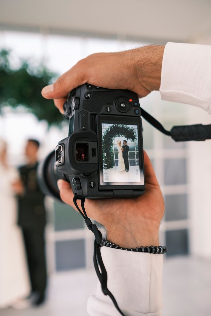 Person holding a camera with a photo of a couple getting married on the screen