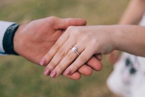 Man holding a woman's hand wearing a sustainable engagement ring