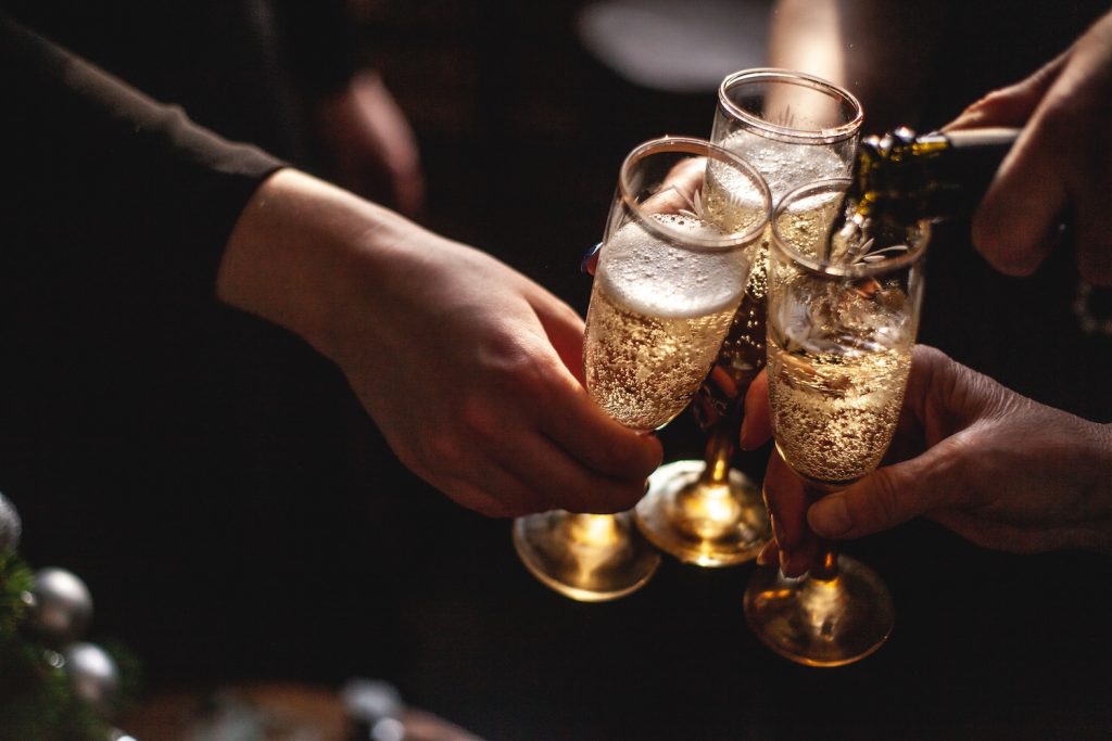 Three champagne glasses getting filled by a person during a bottle of champagne