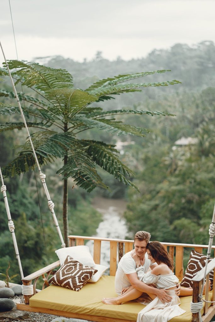 Couple sitting on a day bed in front of rainforest valley