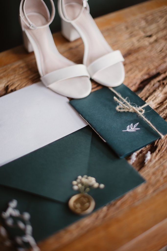 Blank wedding stationary sitting on a table with a pair of white high heels